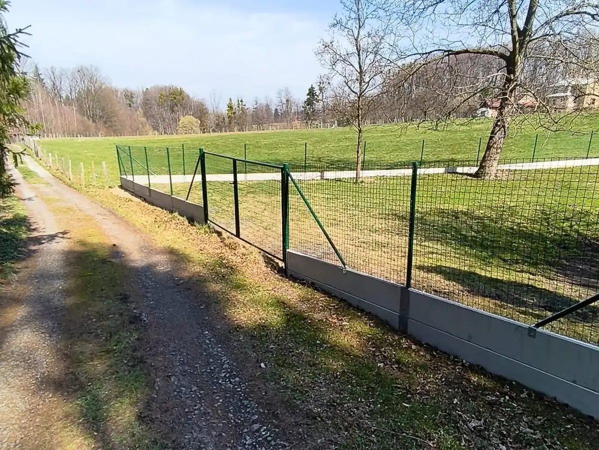 Svařované pletivo s podhrabovými deskami v mírném svahu podél cesty v Malenovicích, 2026